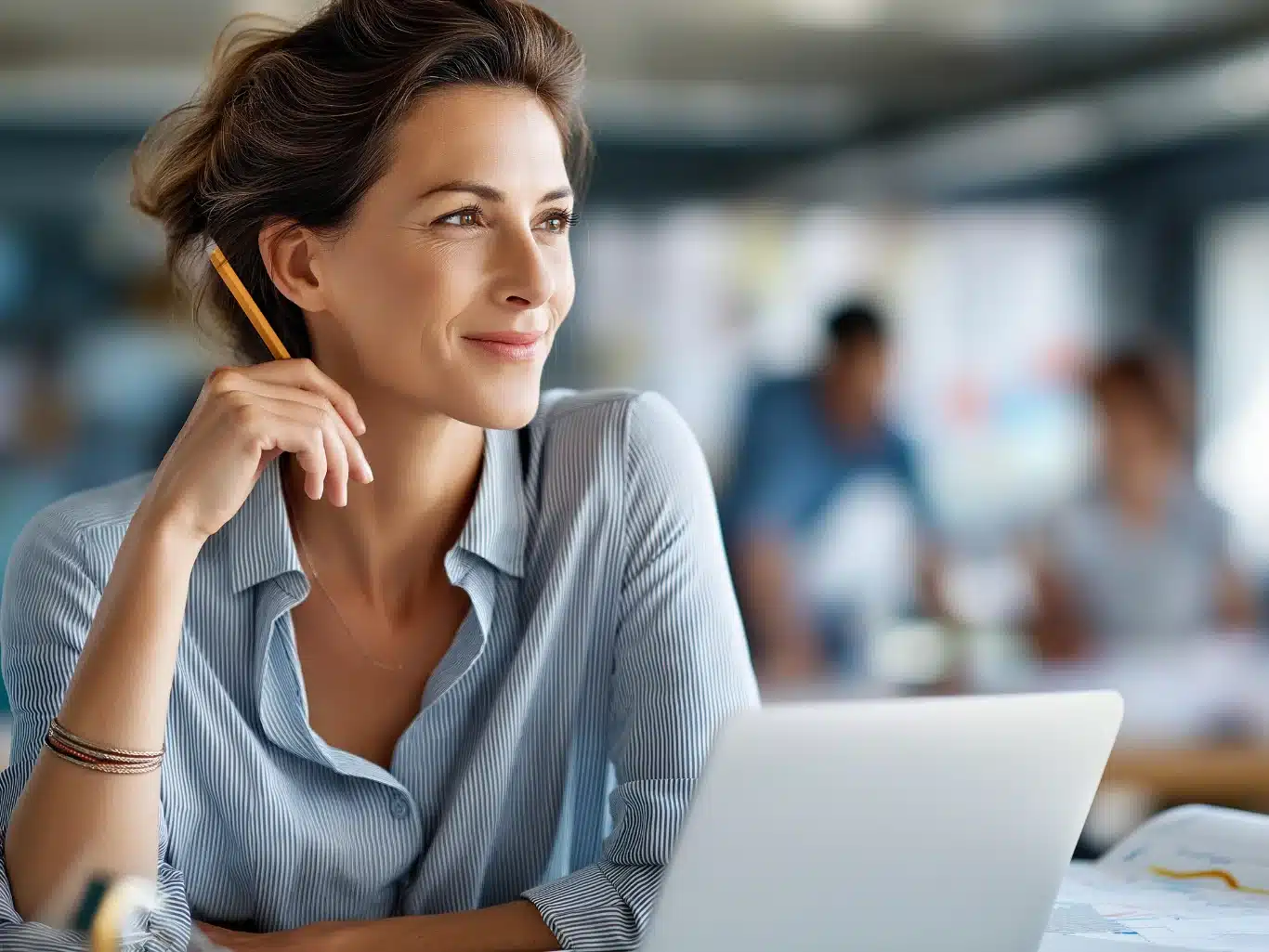 Pensive woman thinking about ideas Focused professional woman with a pencil at her temple and an open laptop